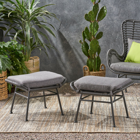 Two grey wovenstyle outdoor ottomans with comfortable seat cushions on a patterned rug