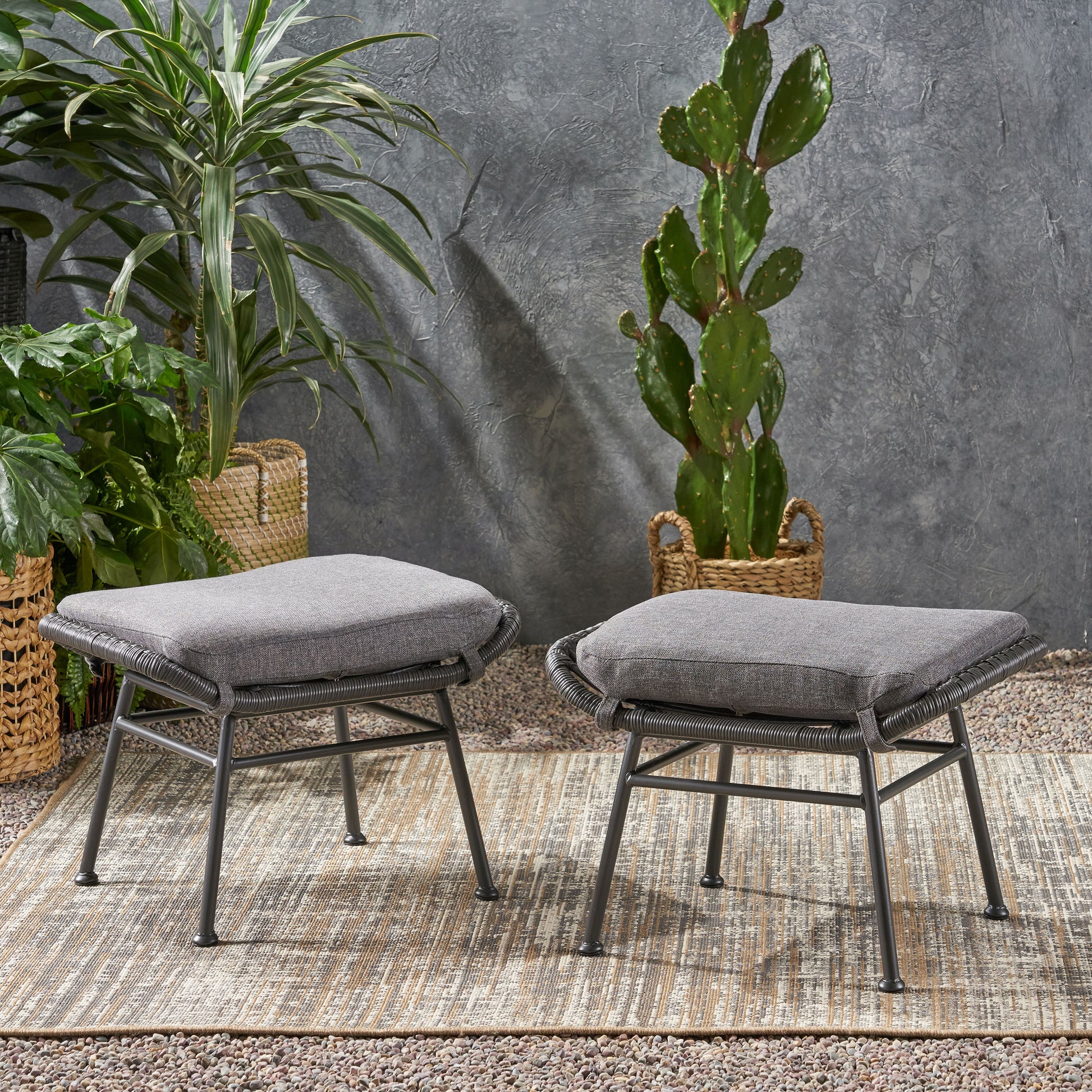Two grey upholstered ottomans with woven rope detailing on a patio rug