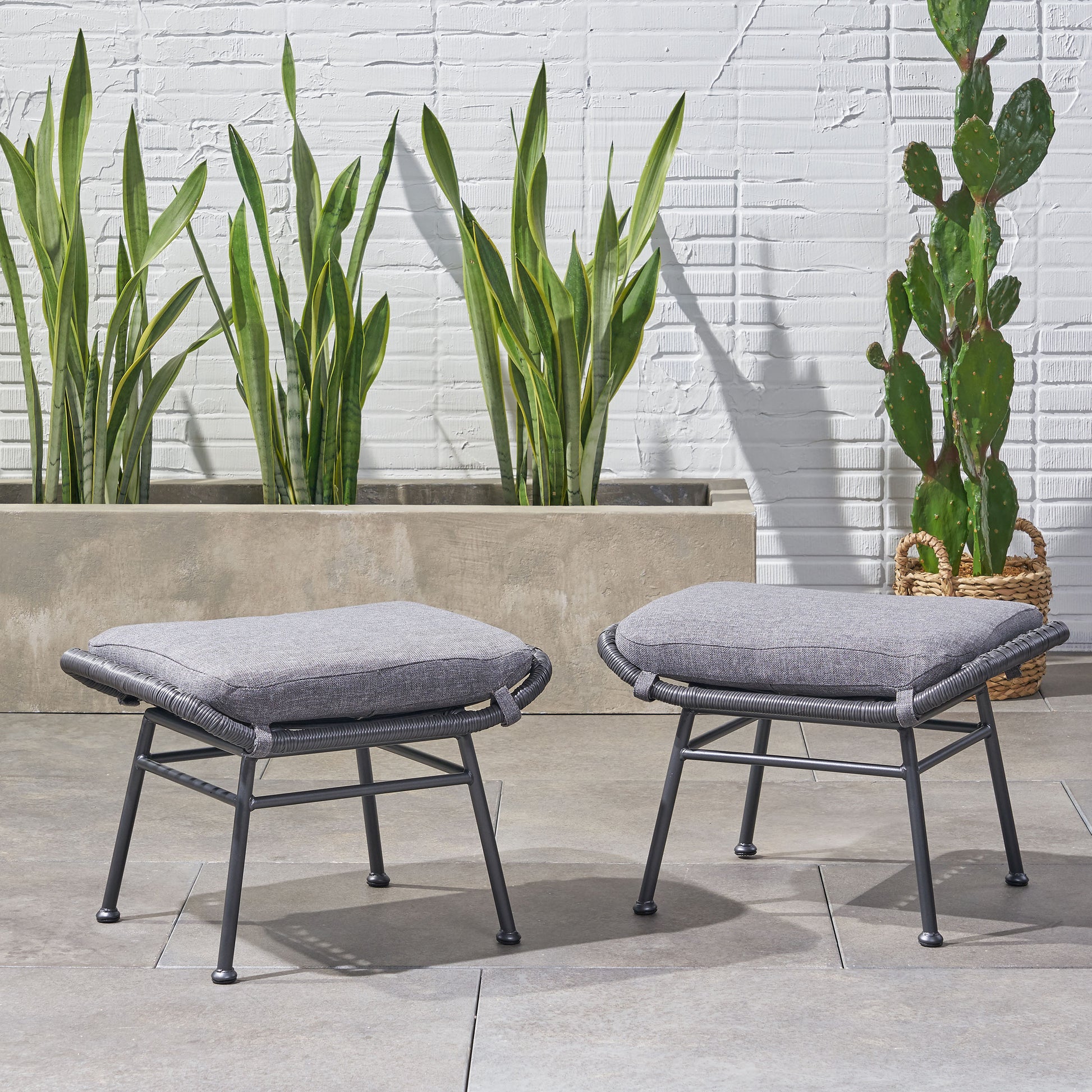 Gray woven outdoor ottoman with plush cushion on metal legs ideal for patio seating