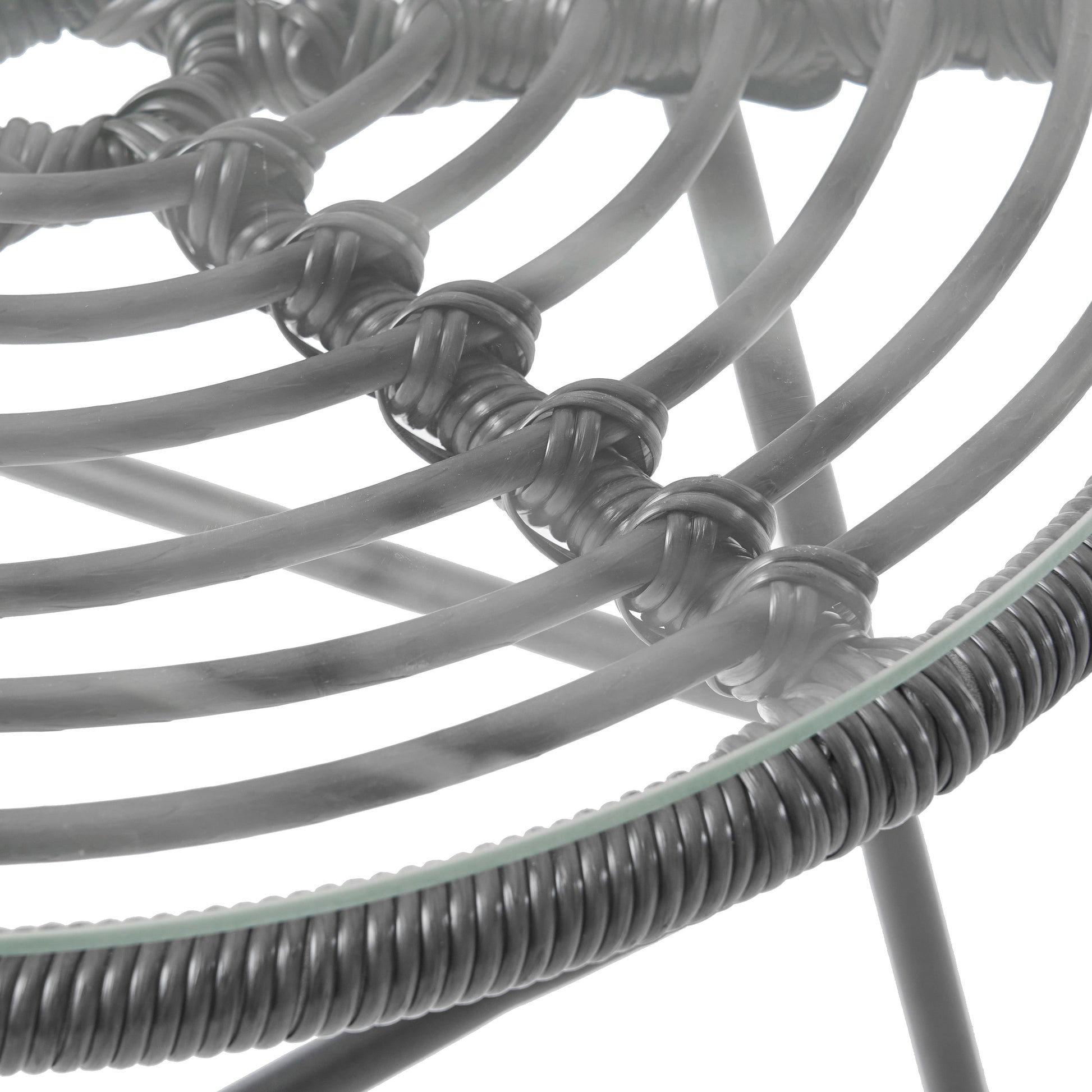 Closeup of woven grey rattan chair frame with glass top detail