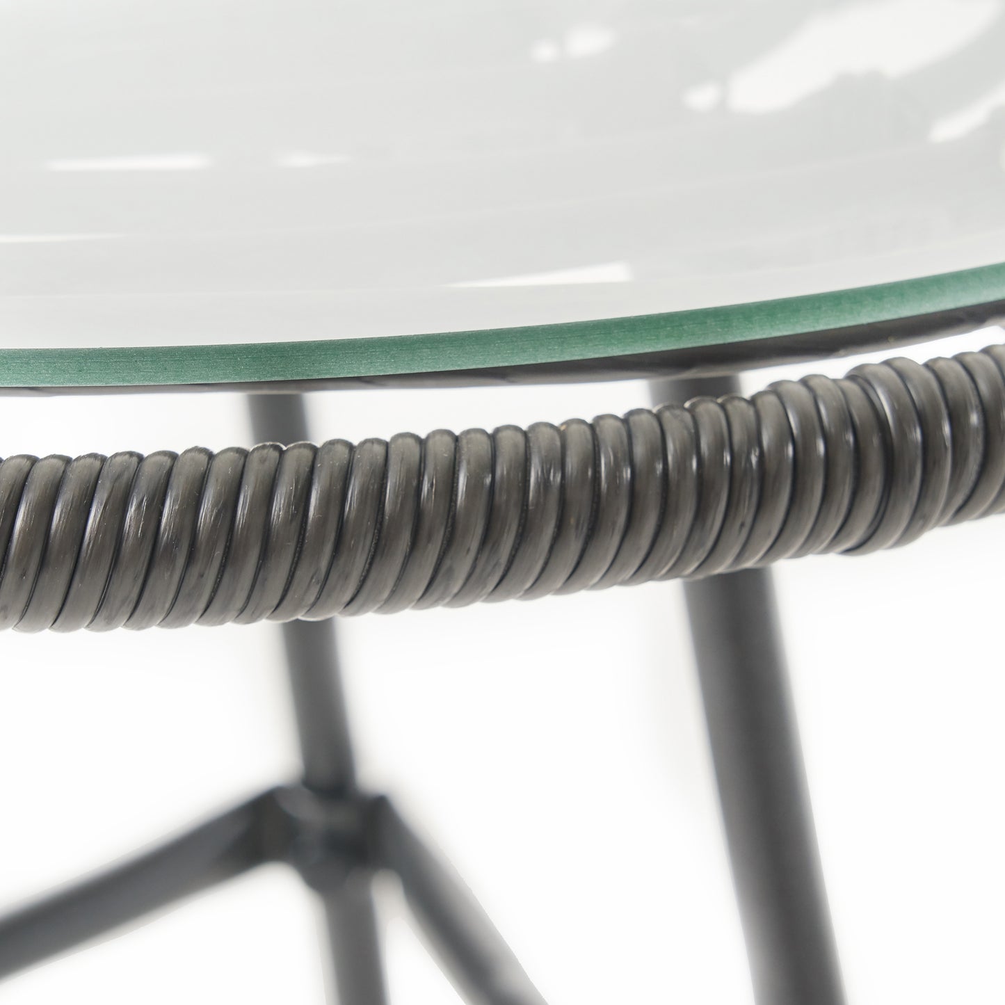 Closeup of a dark gray wicker weave on a chair armrest and clear glass tabletop