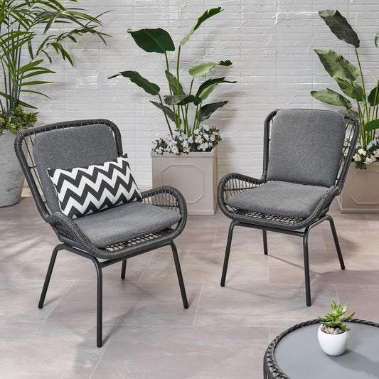 Two dark grey woven wicker patio chairs with cushions one with a chevron pillow