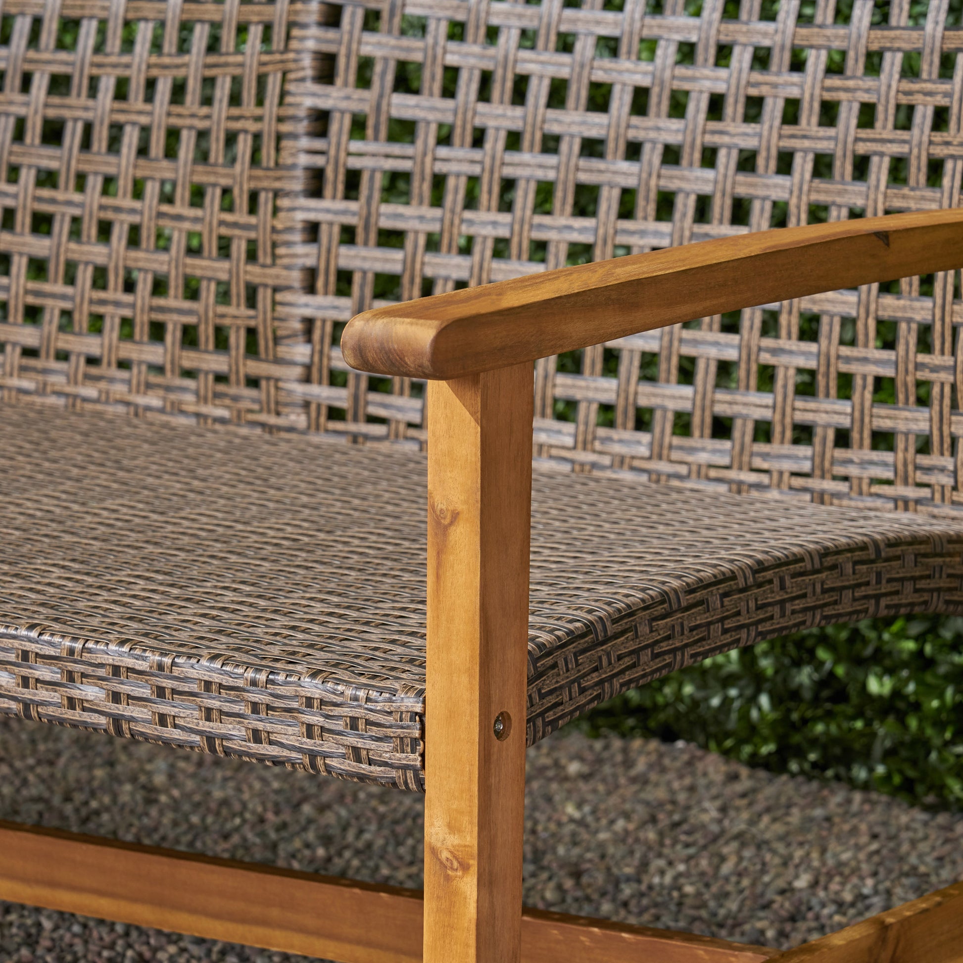 Closeup of a twoseater wicker bench with natural wood armrests ideal for patio seating