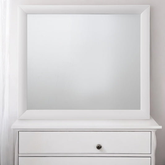 White framed vanity mirror atop a white dresser