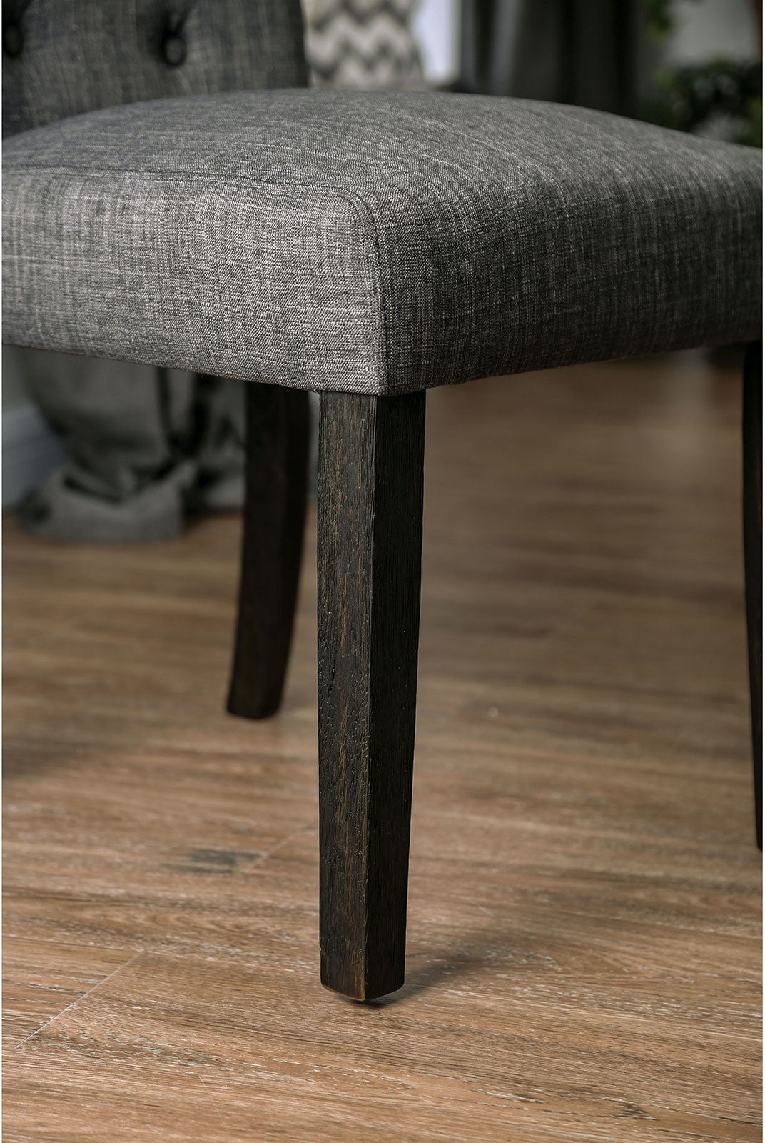 Dark oak wooden chair legs supporting a tufted grey upholstered seat modern design