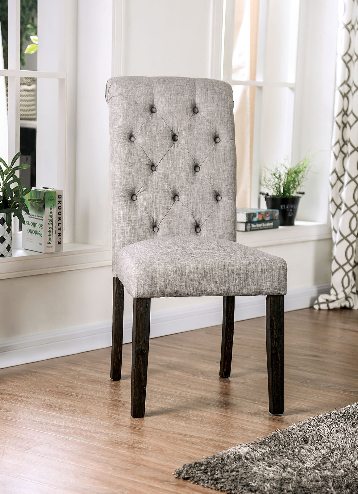 Light grey upholstered dining chair with diamond tufting and dark wood legs