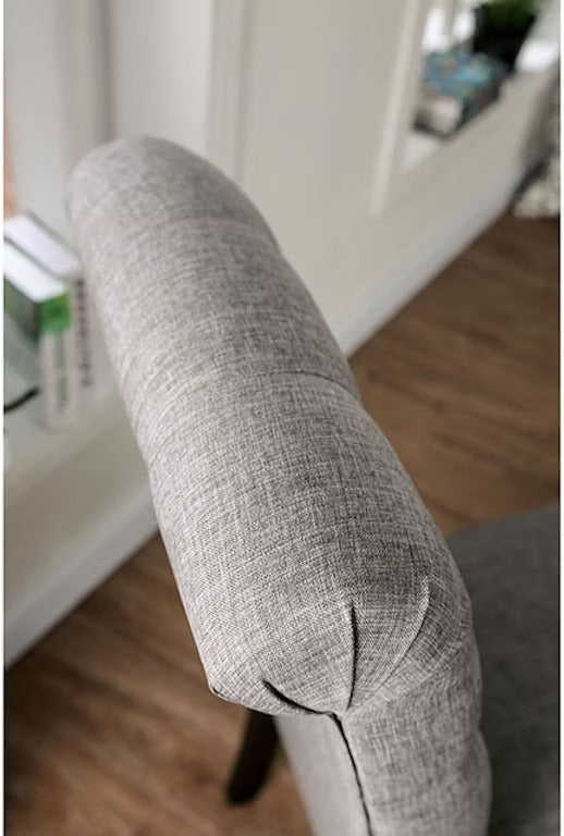 Gray fabric armchair armrest with tufted details and wooden floor background