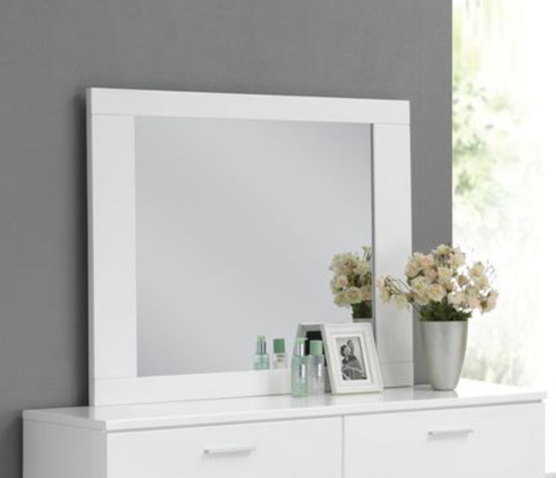 White wooden framed vanity mirror on a dresser with decor