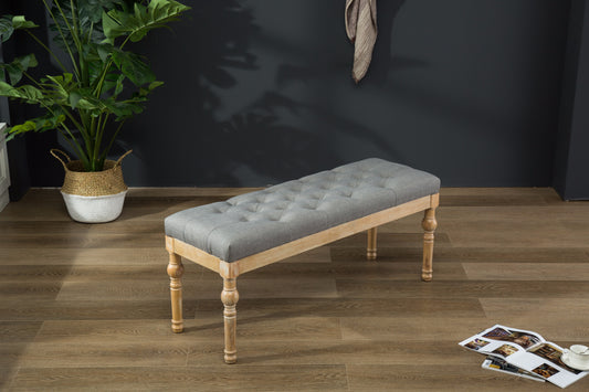 Tufted grey linen bench with carved natural wood legs perfect as a decorative accent bench