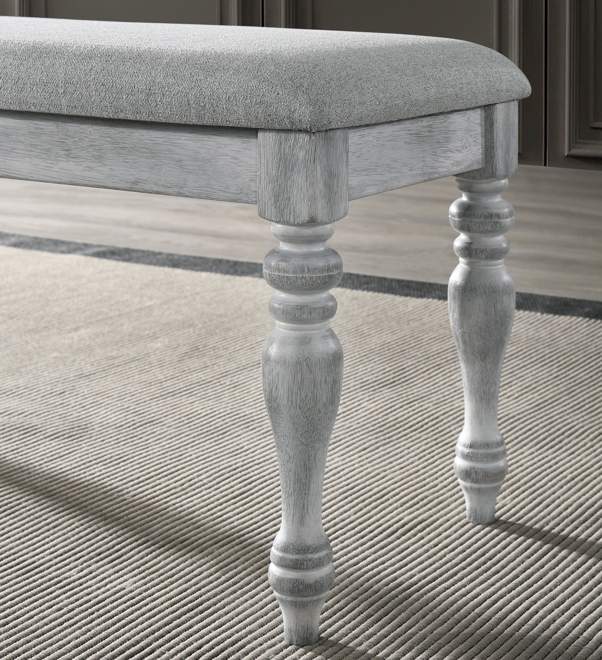 Upholstered grey bench with turned wooden legs