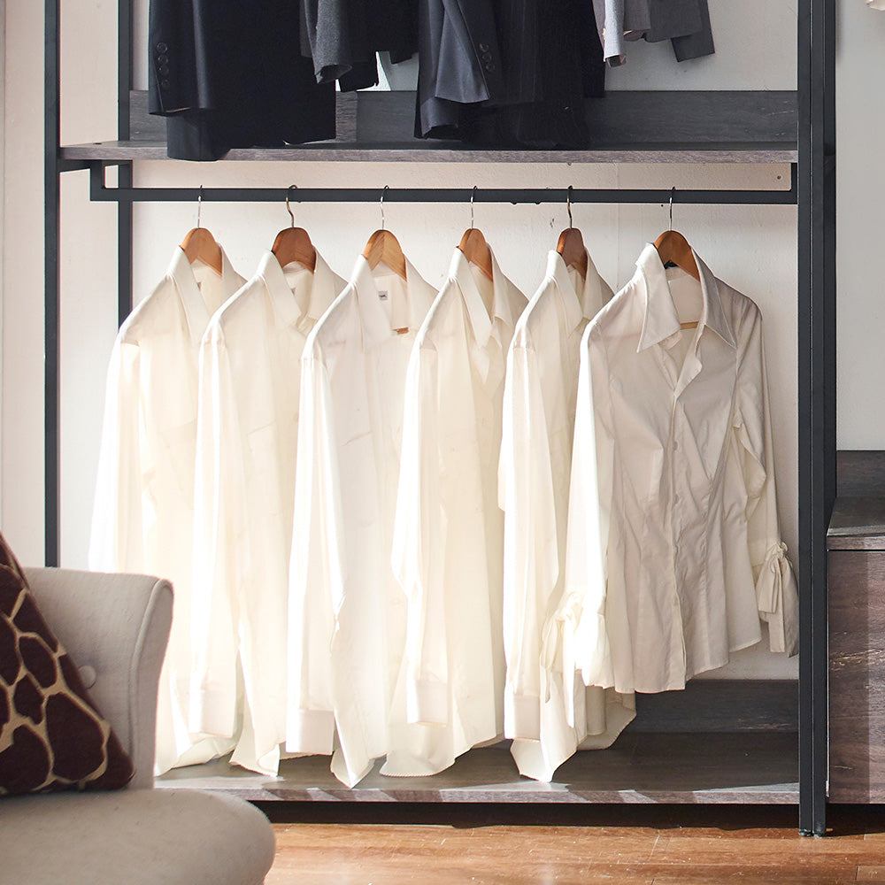 Six creamcolored buttondown shirts hanging on wooden hangers