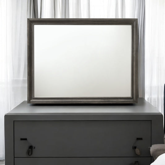 Gray wood frame mirror on dark gray dresser