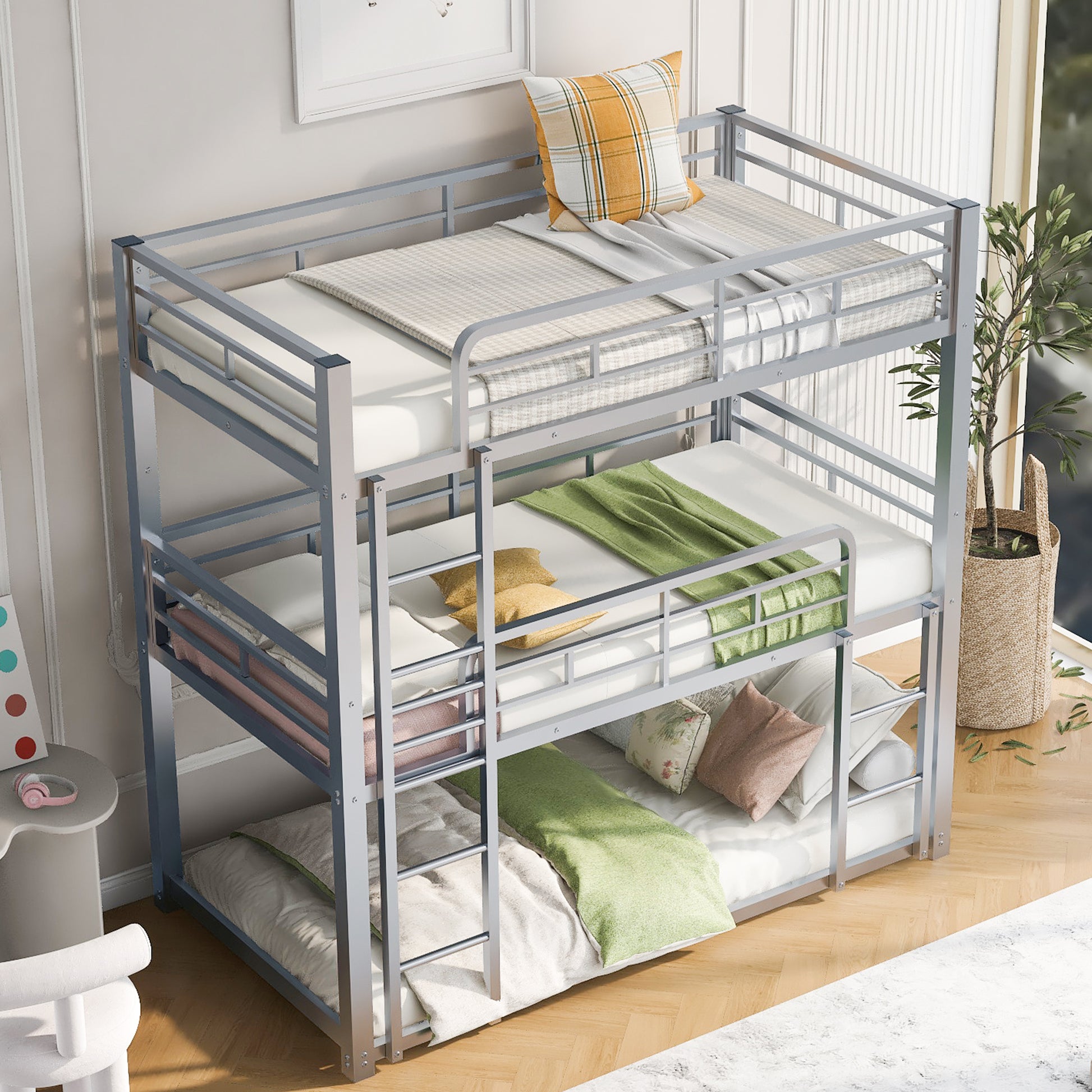 Silver metal triple bunk bed with white mattresses and colorful pillows