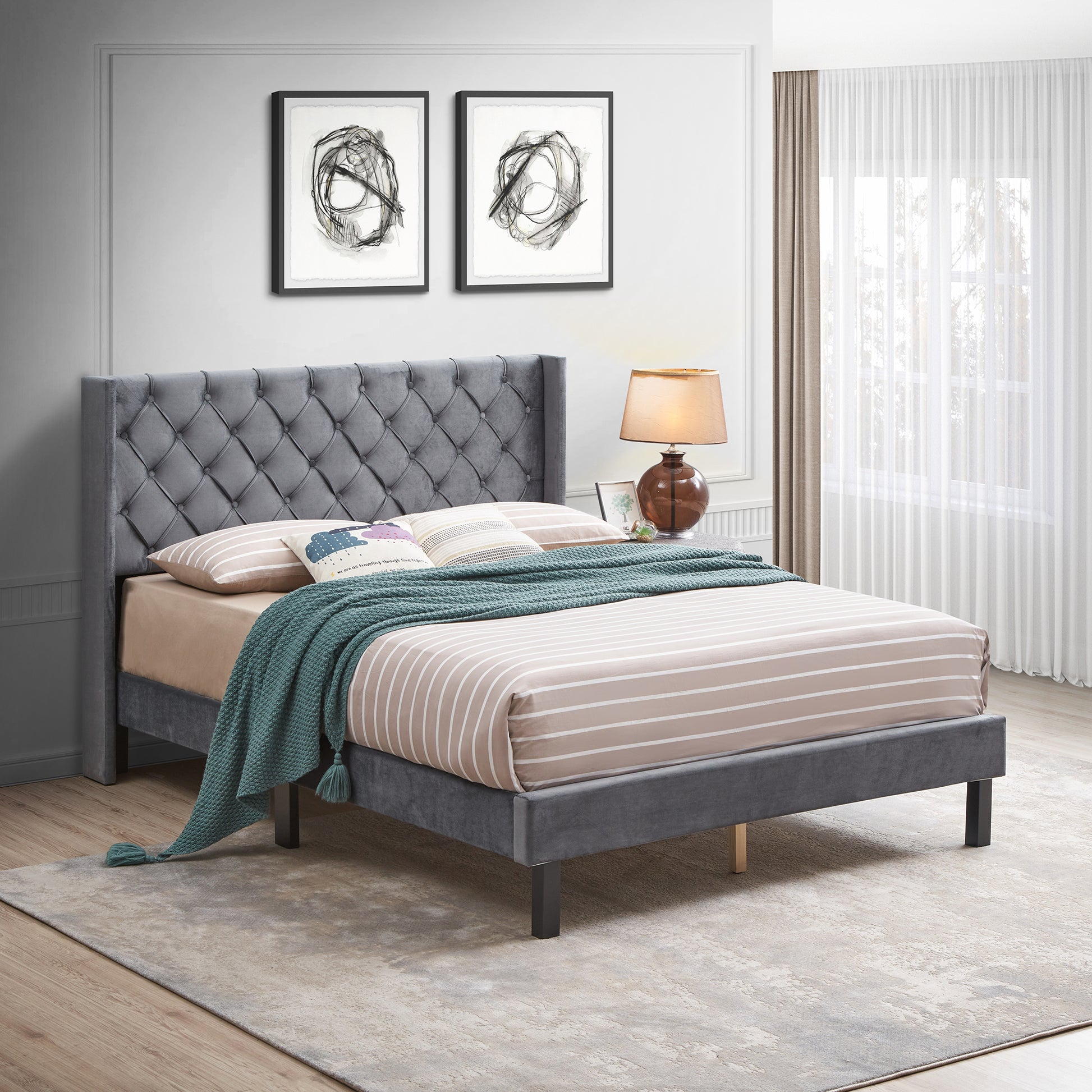 Gray velvet tufted wingback bed frame with a queen mattress and striped bedding