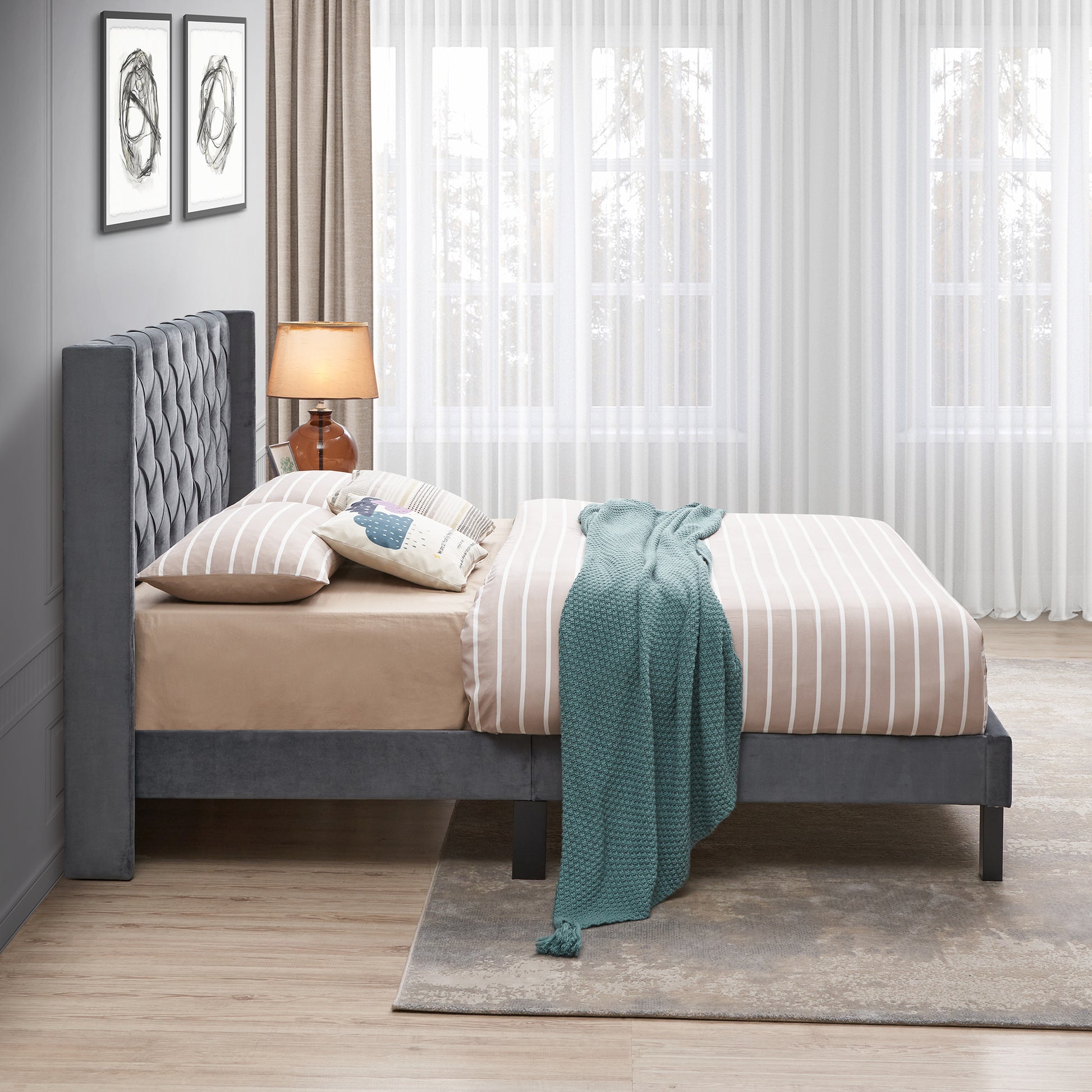 Gray velvet platform bed with tufted headboard and striped bedding