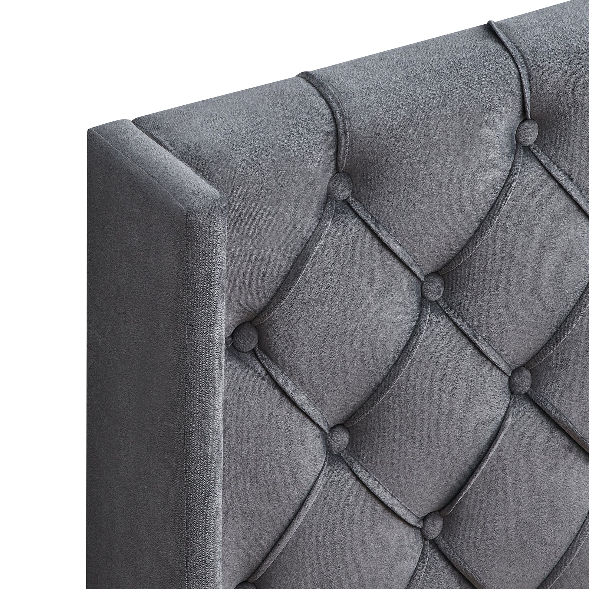 Closeup of a grey velvet tufted headboard with diamondshaped stitching and button accents