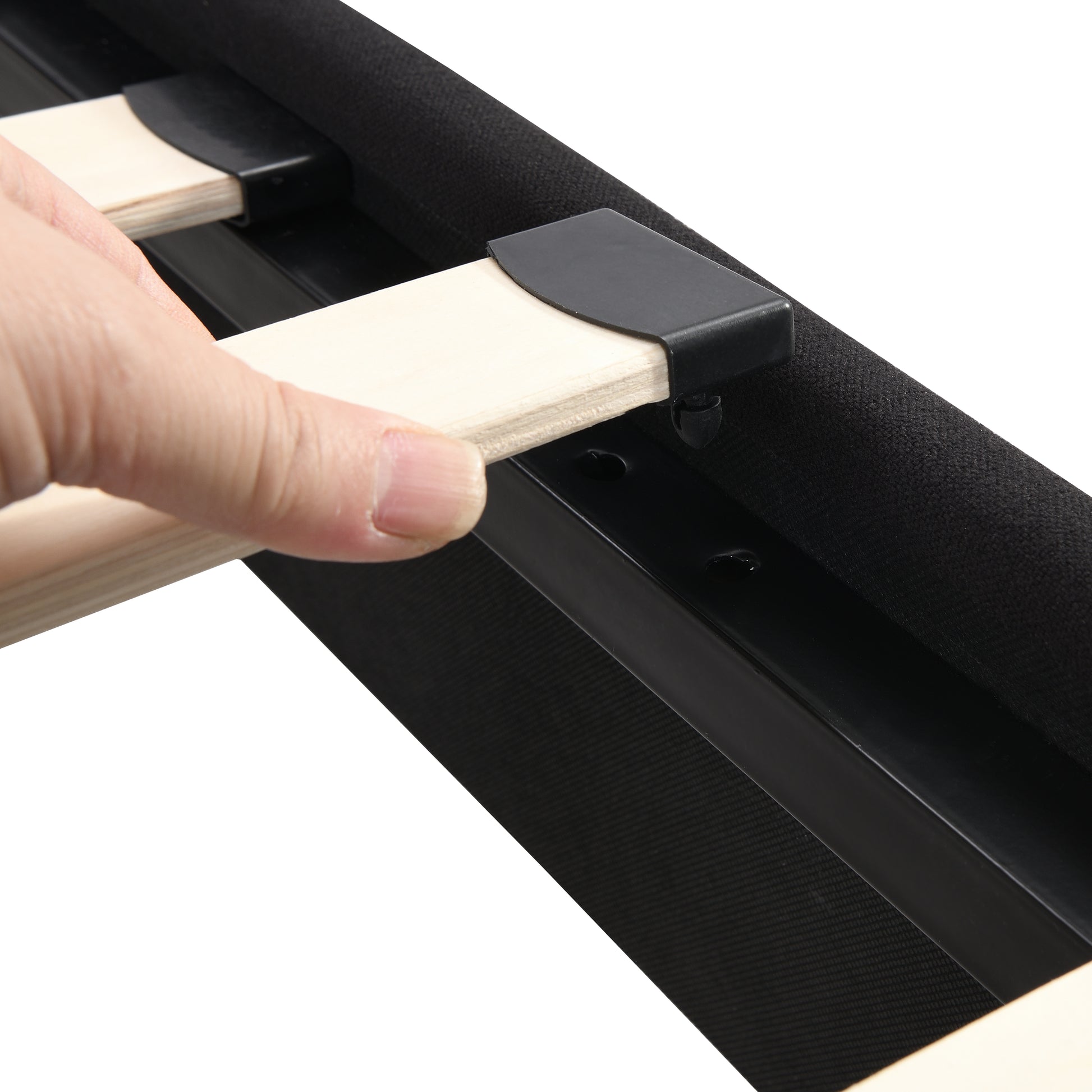 Closeup of hand inserting wooden slat into black bed frame bracket