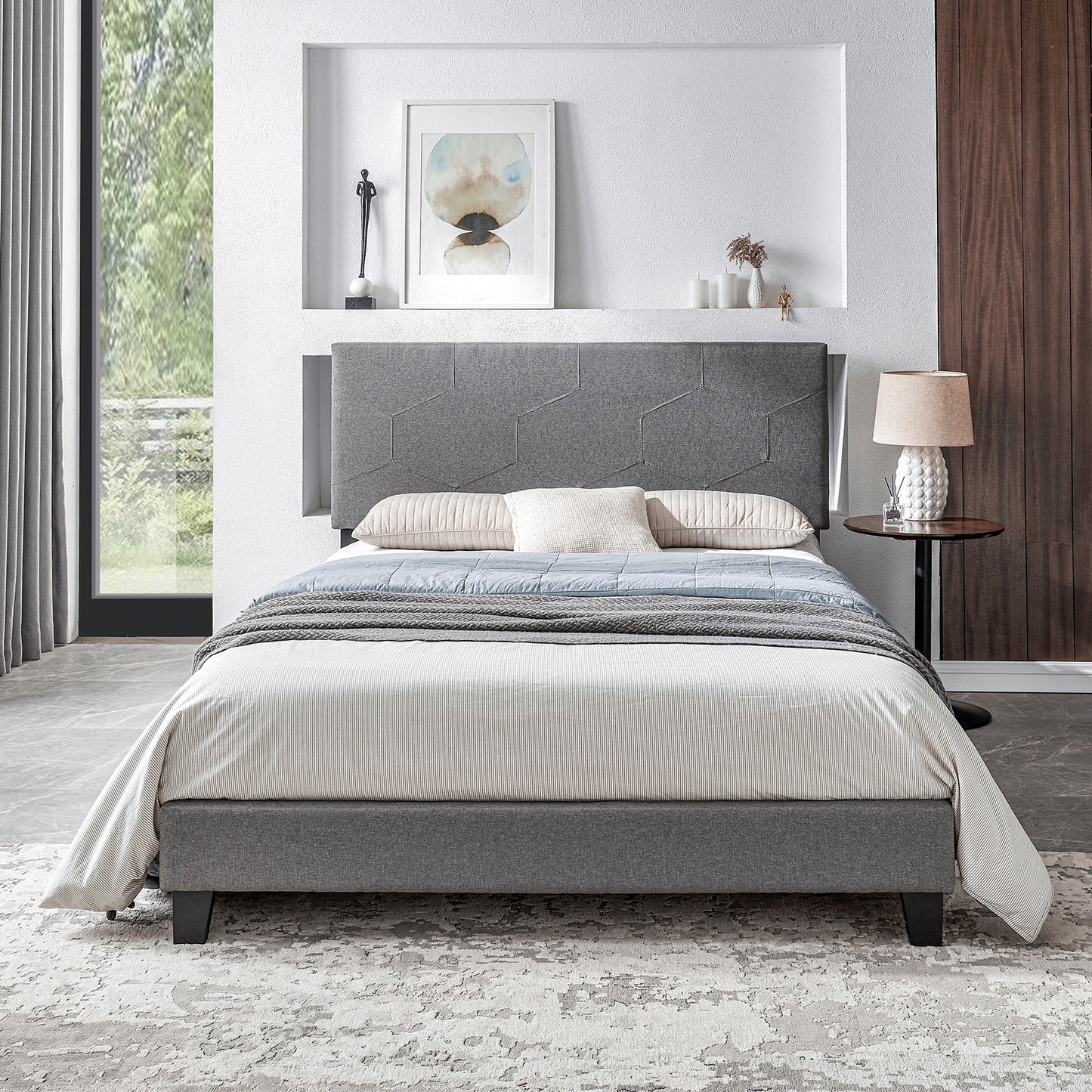 Grey upholstered bed frame with geometric headboard and striped duvet