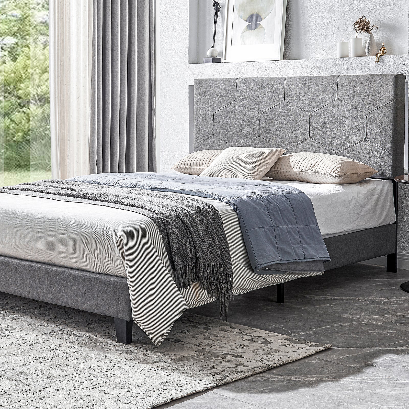 Gray fabric bed frame with geometric headboard and striped bedding