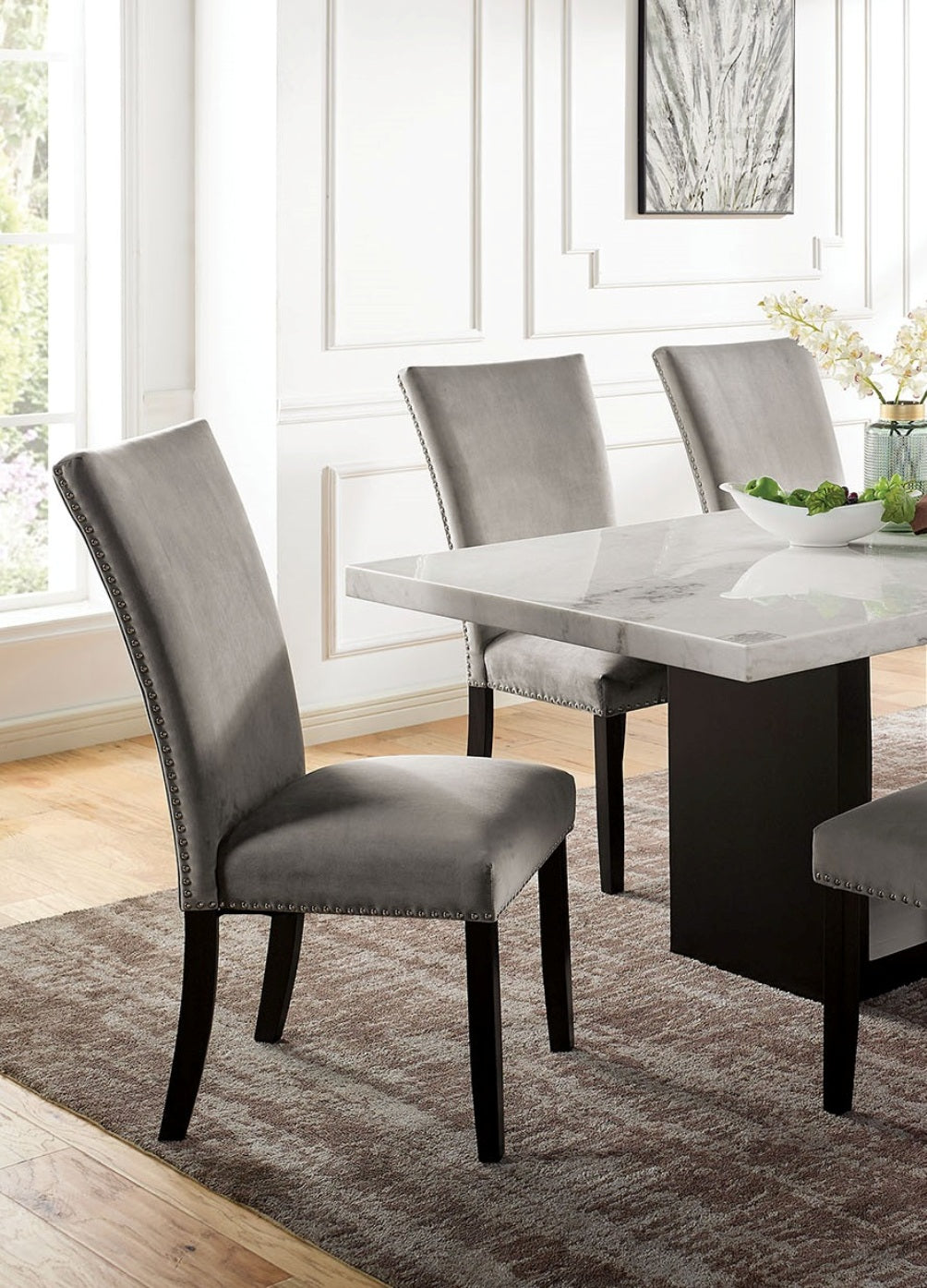 Gray velvet dining chair with silver nailhead trim and dark wood legs