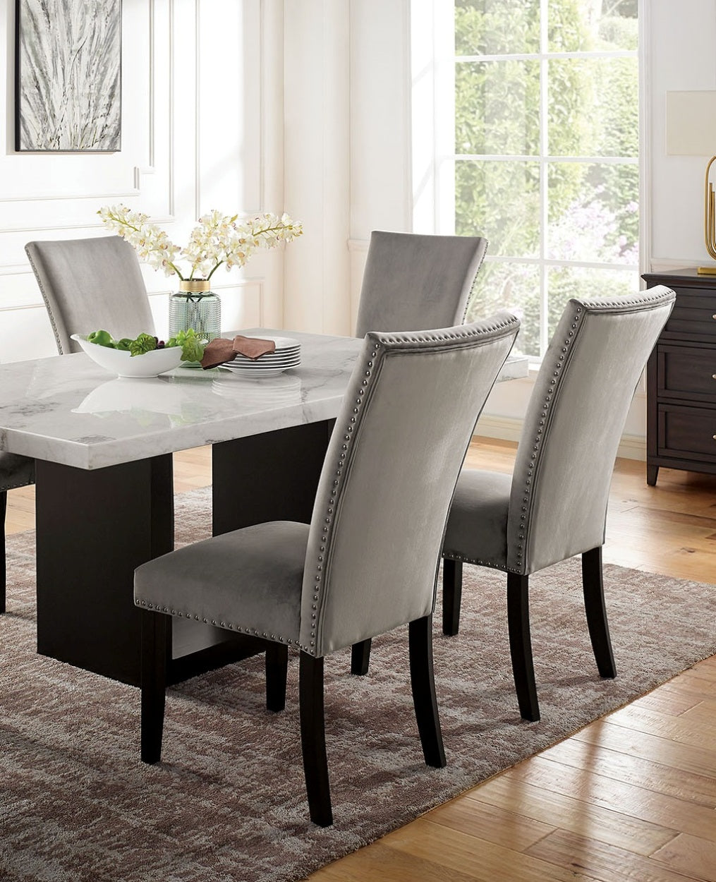 Elegant grey velvet dining chairs with nailhead trim around a marbletop table