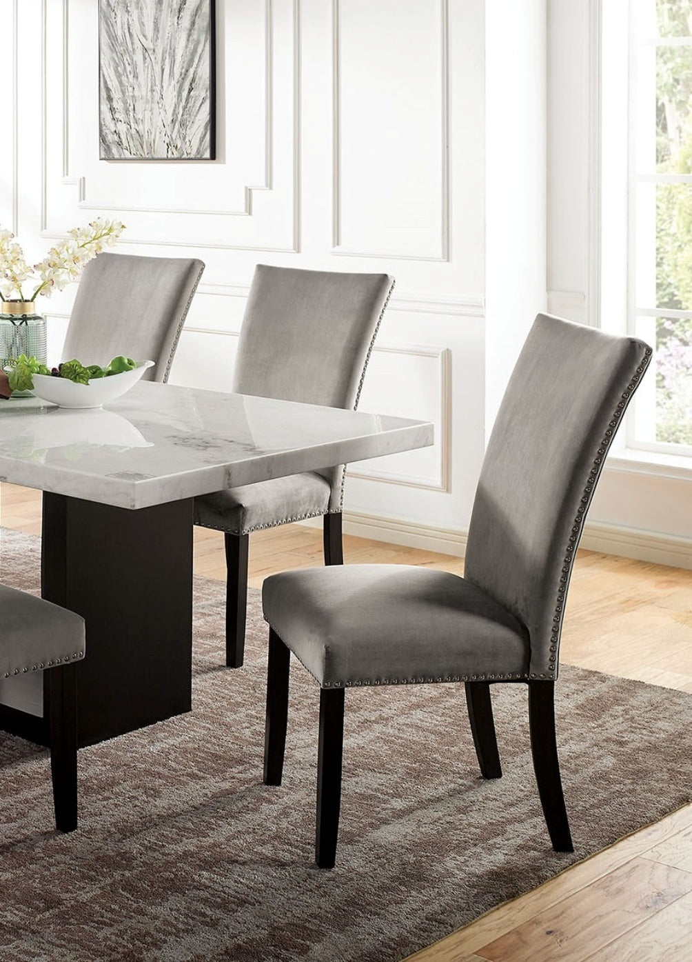Gray velvet dining chair with studded trim and dark wood legs