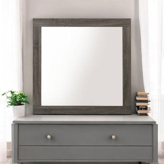 Rustic wood framed mirror mounted on a grey dresser with decorative plants and books