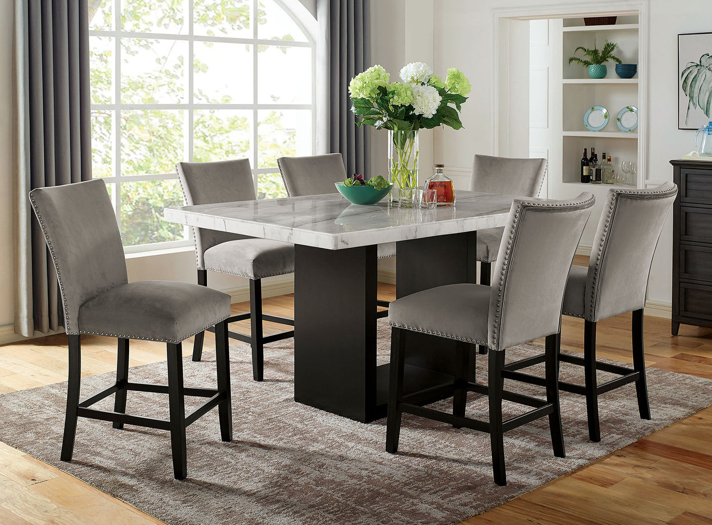 Grey velvet counter stools with nailhead trim surround a marbletop counter height dining table
