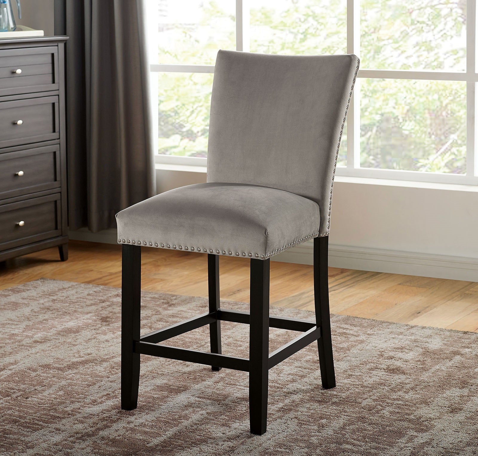 Grey velvet bar stool with silver nailhead trim and dark wood legs