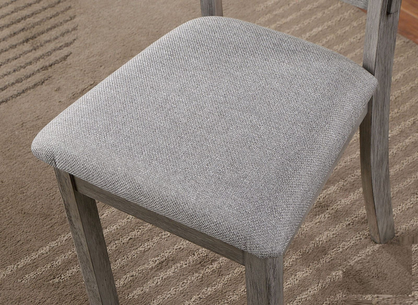 Gray fabric dining chair seat detail on textured rug