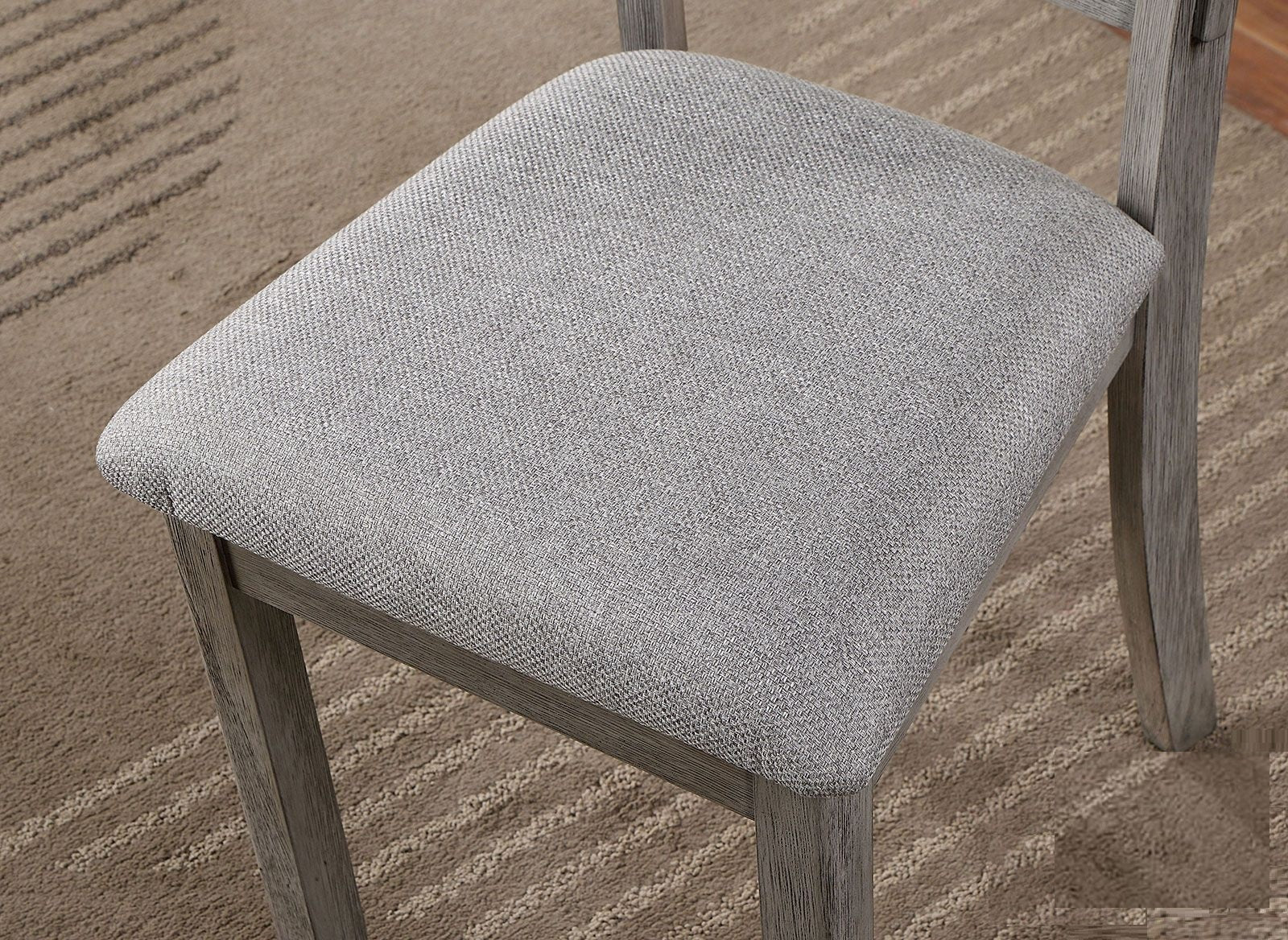 Gray fabric dining chair seat detail on textured rug