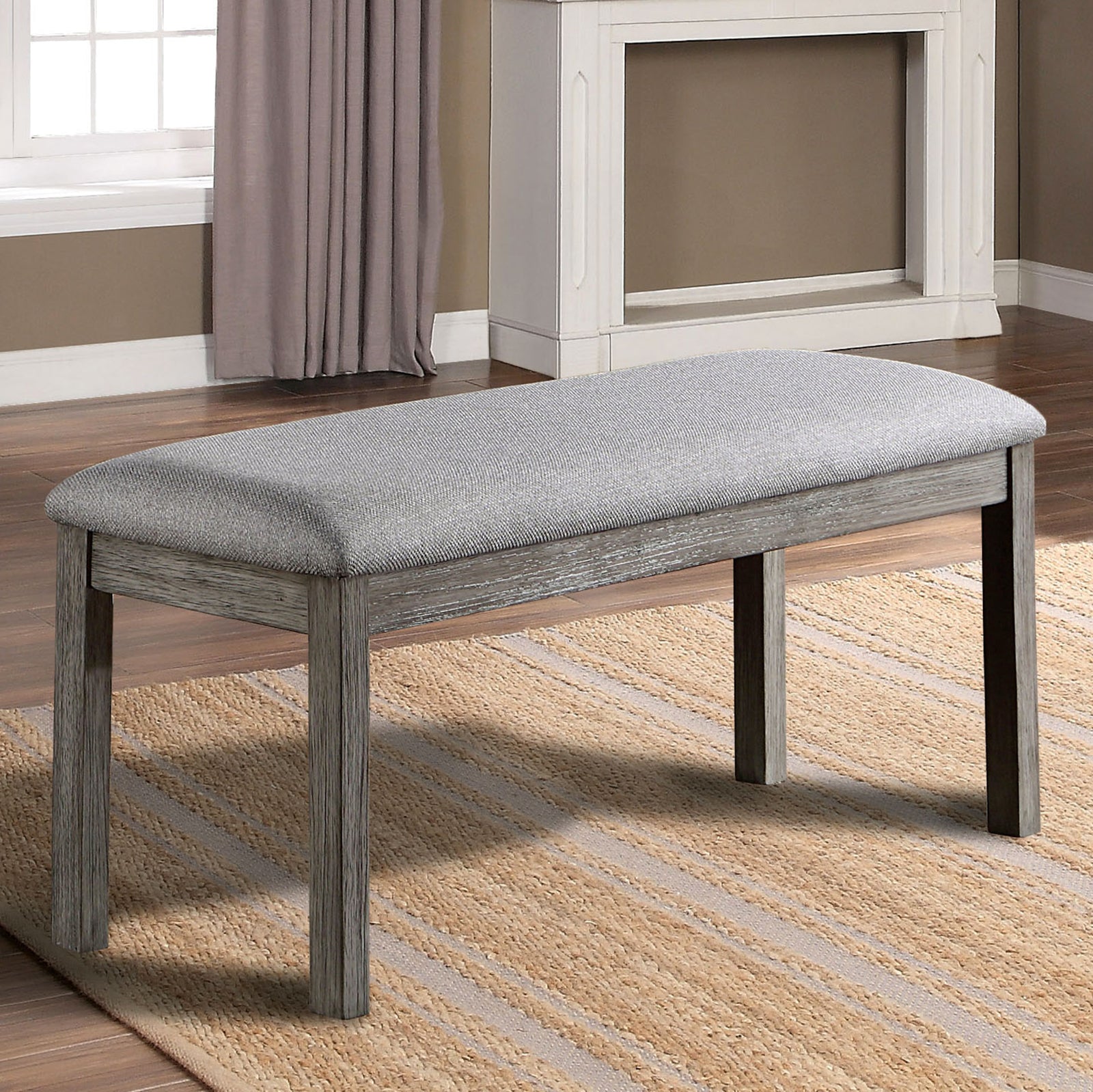 Grey upholstered bench with rustic wood legs on striped rug