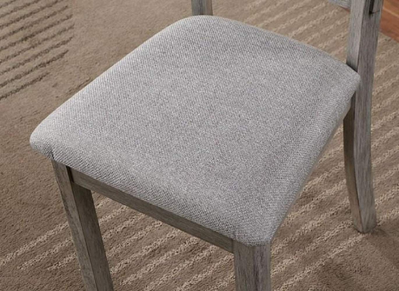 Closeup of a grey fabric upholstered seat on a distressed wood dining chair