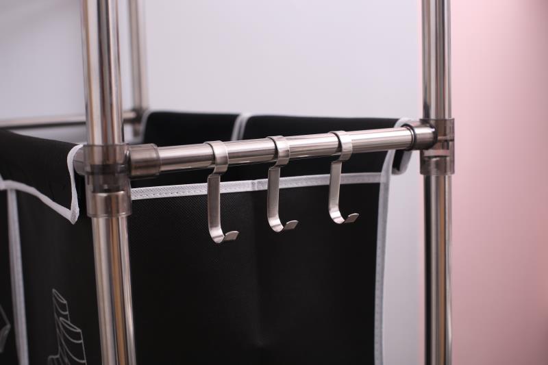 Closeup of a black fabric laundry basket with silver metal hooks attached to a support rod