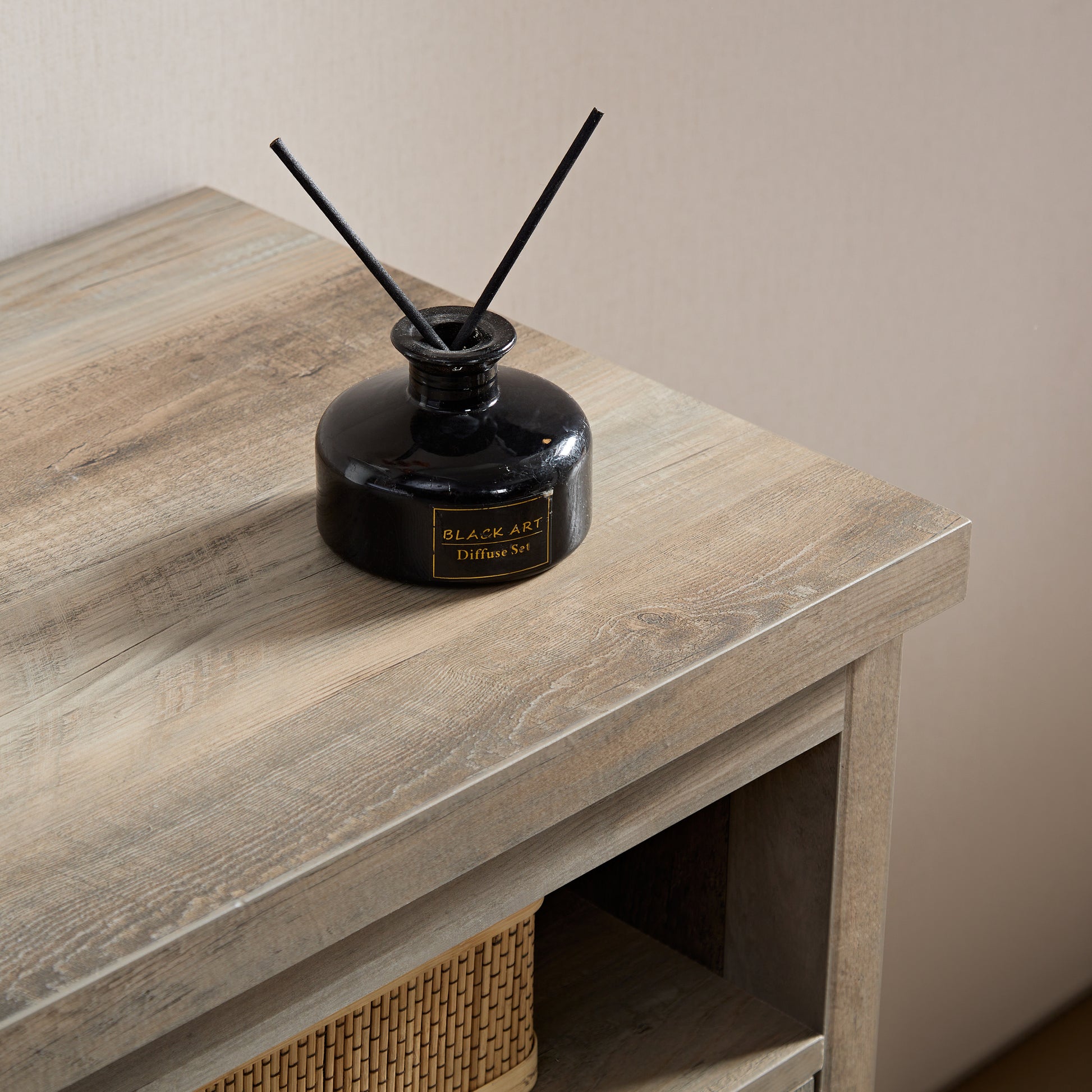 Black glass reed diffuser with wooden reeds on distressed wood surface