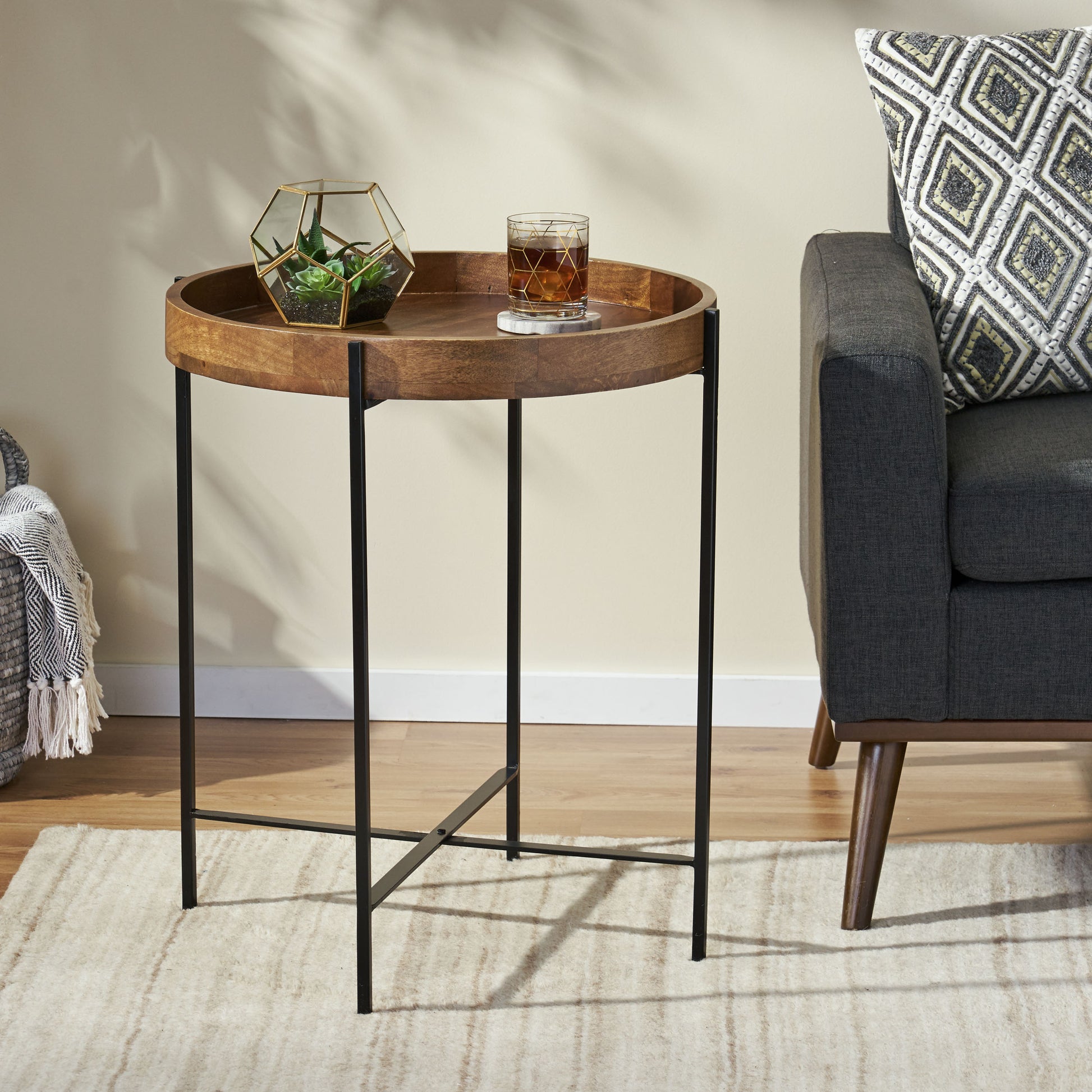 Round wood side table with geometric metal base and tray top for drinks