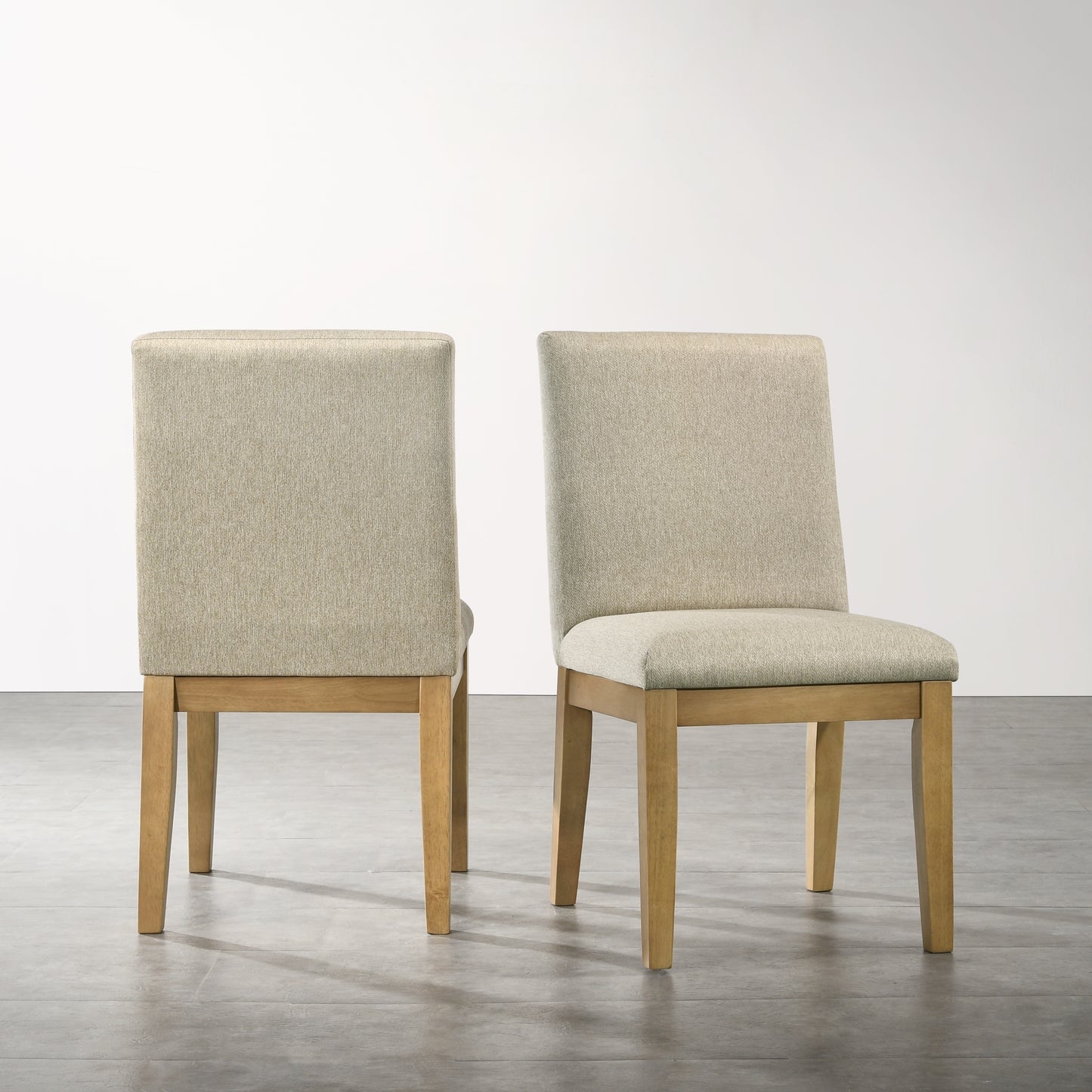 Two beige upholstered dining chairs with natural wood legs in a modern style