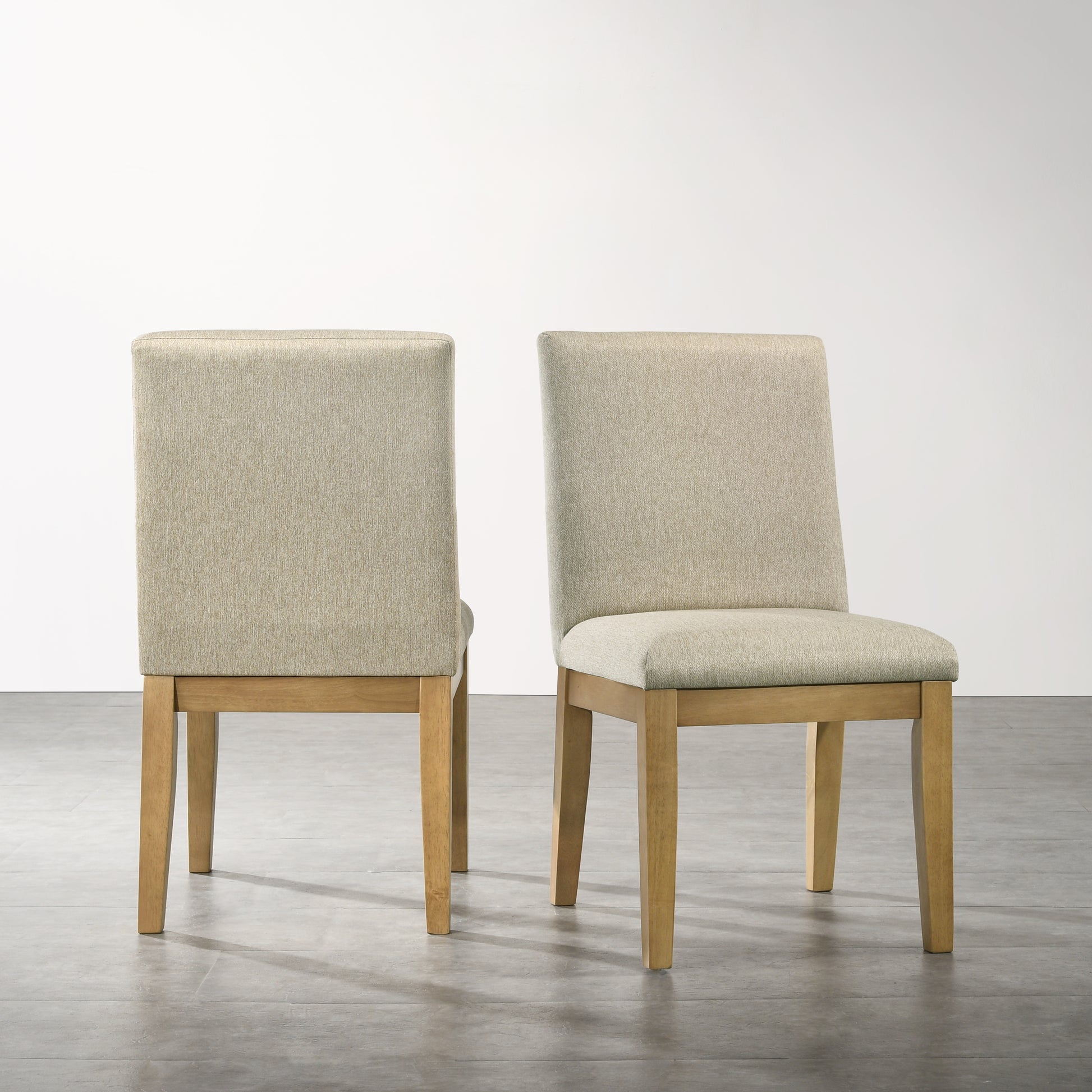 Two beige upholstered dining chairs with natural wood legs in a modern style