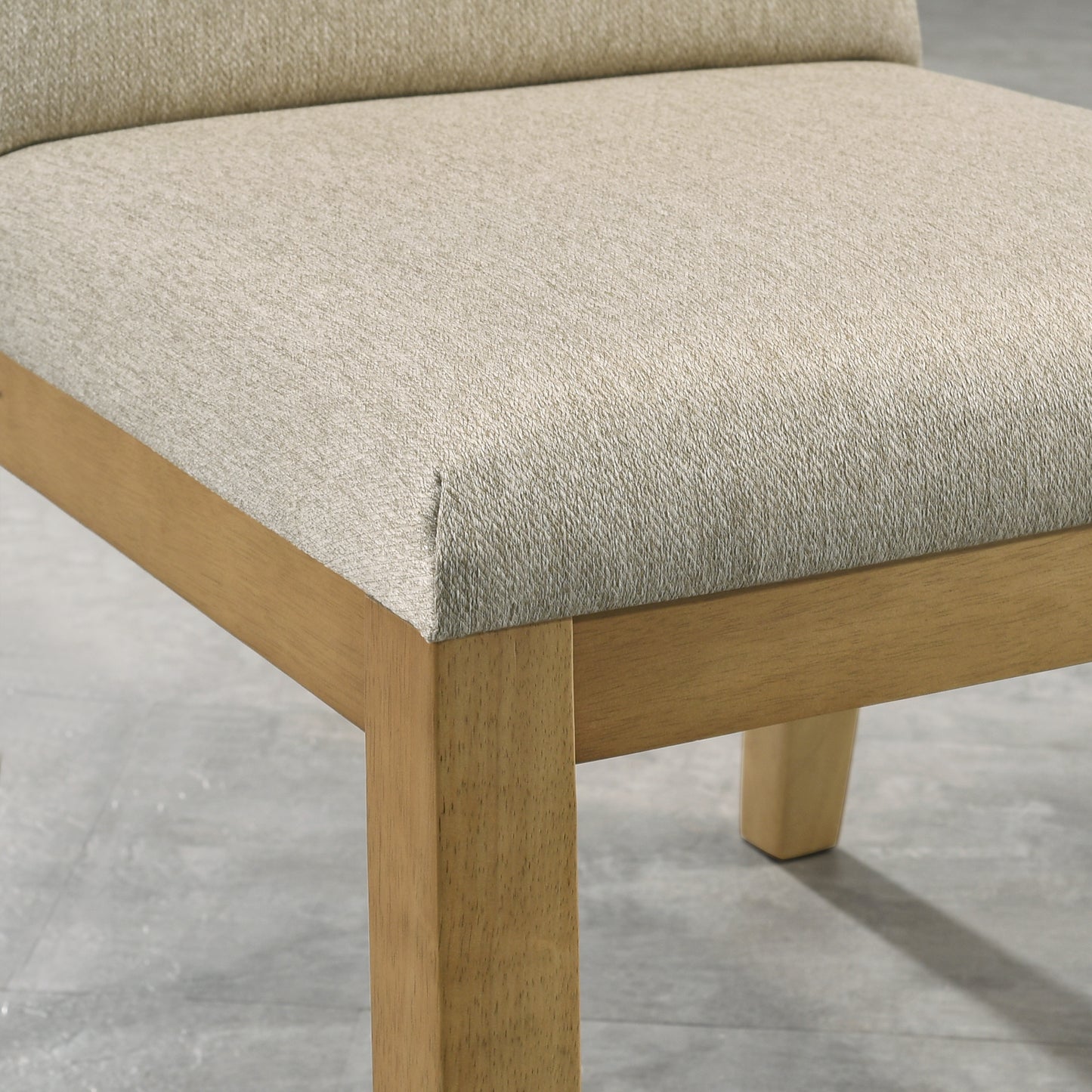 Closeup of a beige textured fabric upholstered dining chair seat with natural wood legs