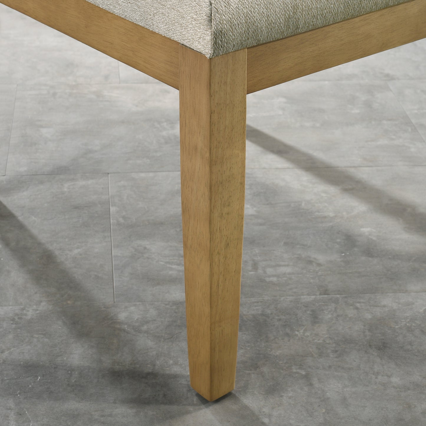Closeup of a light brown wooden dining chair leg on a gray tile floor