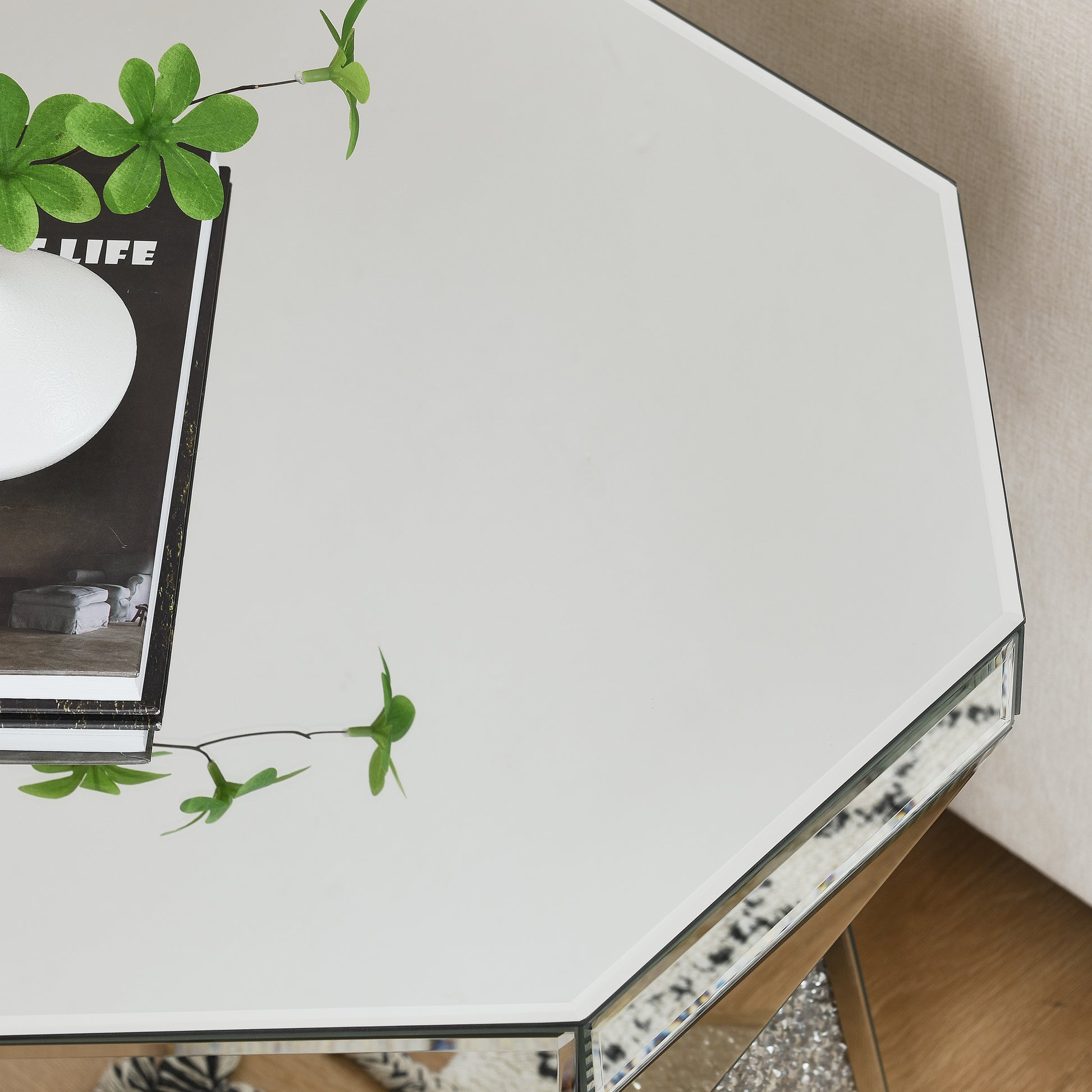 Octagonal mirrored coffee table with decorative greenery and stacked books