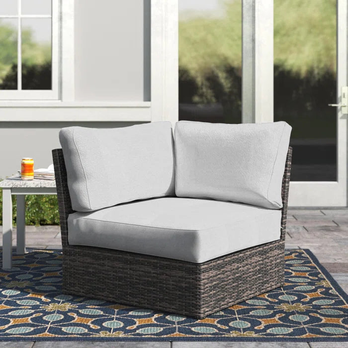 Dark brown wicker outdoor sectional corner chair with light grey cushions on patio rug