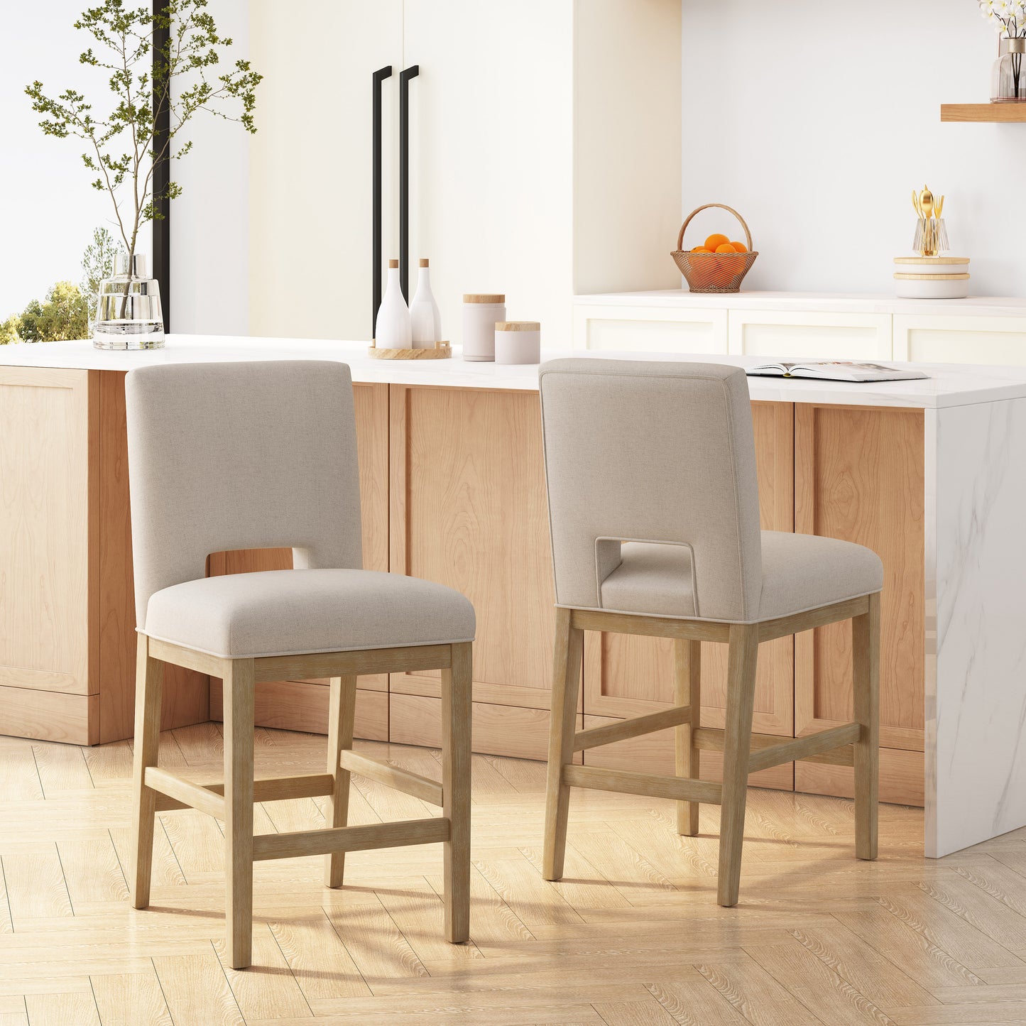 Two beige upholstered counter stools with natural wood legs and a cutout back detail in a modern kitchen setting