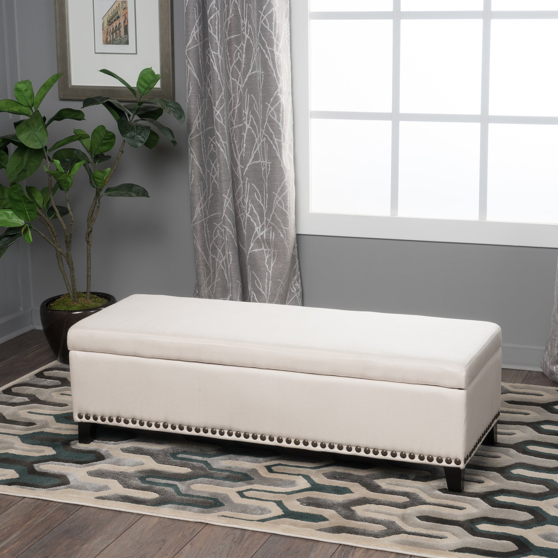 Cream fabric storage ottoman with decorative nailhead trim perfect for entryway or bedroom organization