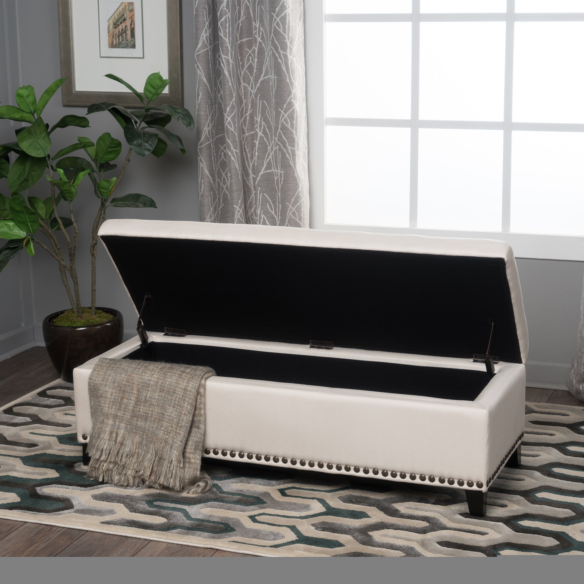 White storage ottoman with decorative nailhead trim and an open lid revealing black interior