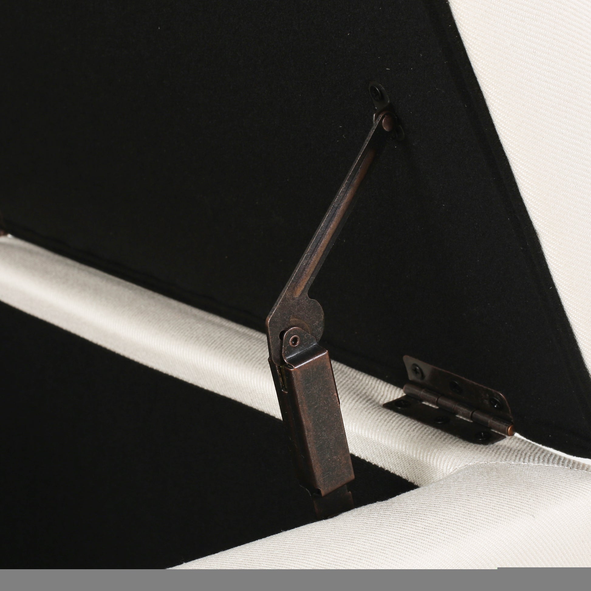 Closeup of a dark metal hinge mechanism for a storage ottoman lid