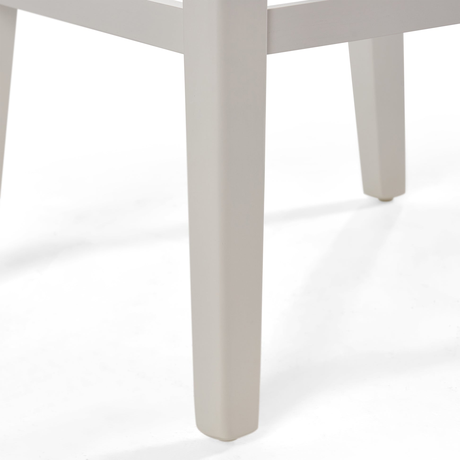 Close up of a modern beige dining chair leg showing square profile and small foot