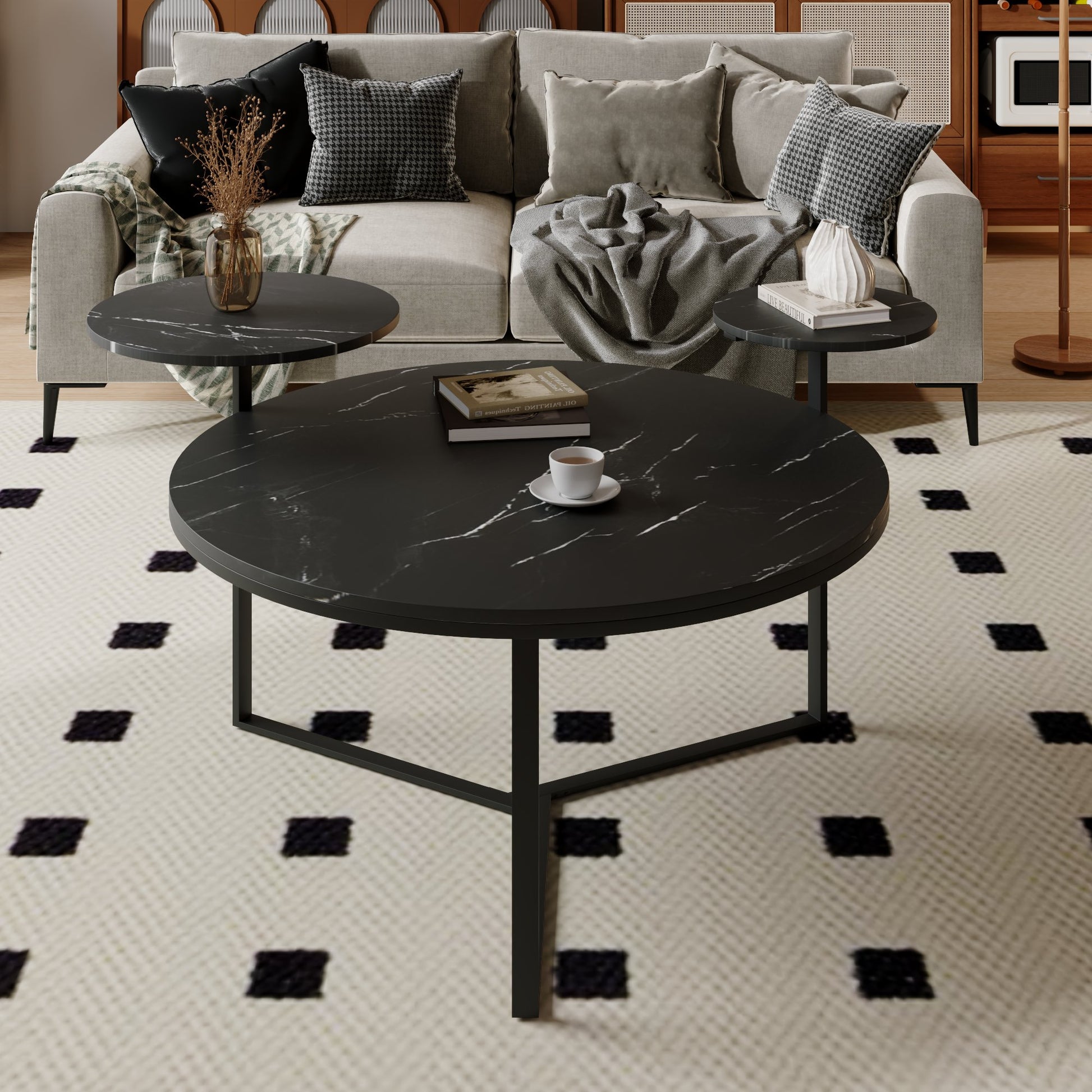 Round black marble coffee table with white veining and metal base holding books and a mug