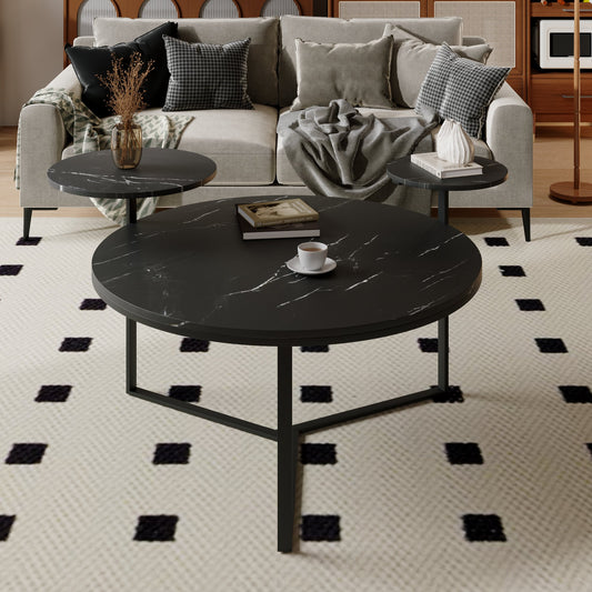 Round black marble coffee table with white veining and metal base holding books and a mug