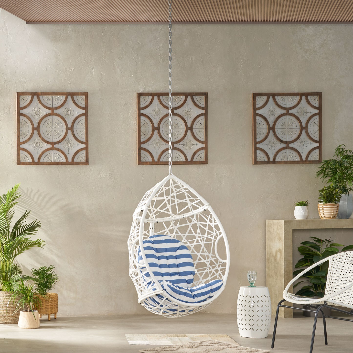 White wicker egg chair with blue striped cushion perfect for outdoor relaxation